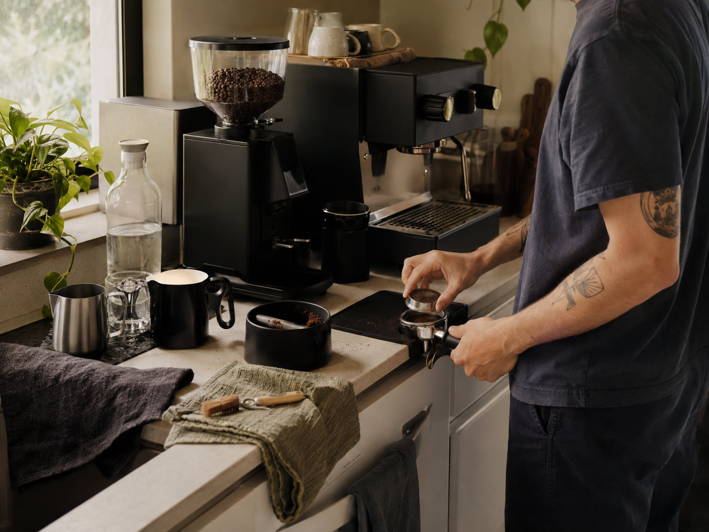 A complete home espresso station is active with grinding, milk tools, and cleanup supplies.